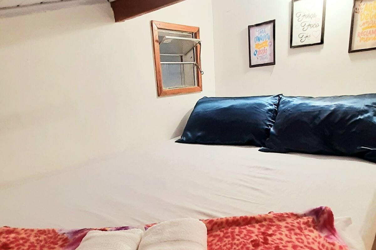 A bedroom with a bed, a window, and three framed pictures on the wall.