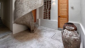 A modern interior with a spiral staircase, a wooden door, and a large pot. - Hotel Atia (Guadalajara)