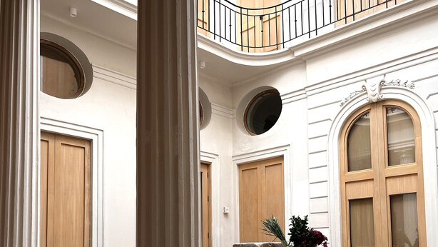 A spacious interior with a checkered floor, large wooden doors, and a balcony with a metal railing. - Hotel Atia (Guadalajara)