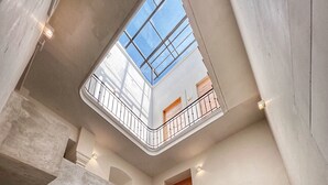 A modern interior with a spiral staircase, a skylight, and a wooden door. - Hotel Atia (Guadalajara)