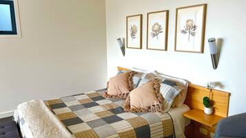 A neatly arranged bedroom with a bed, a bedside table with a lamp, and a chair.