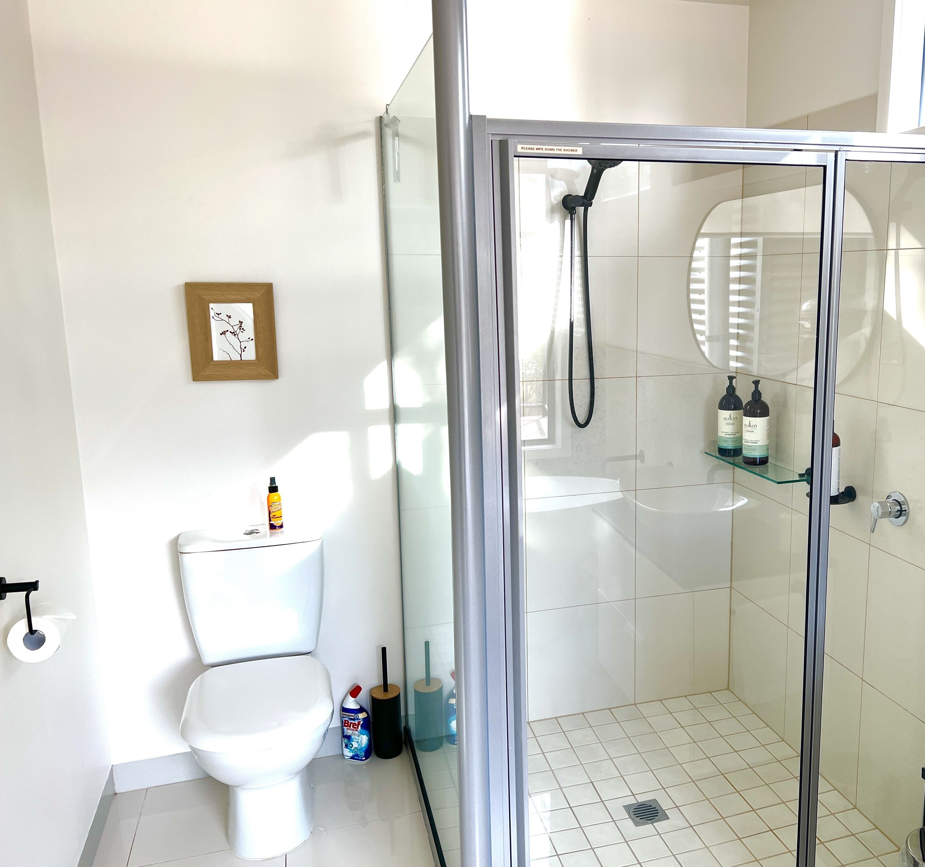 Un bagno moderno con il water, uno spazio doccia in vetro e un lavandino.