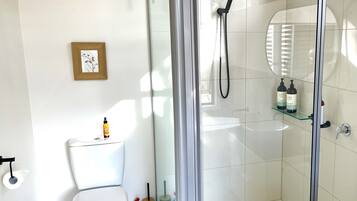 Un bagno moderno con il water, uno spazio doccia in vetro e un lavandino.