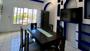 A dining area with a long table, chairs, a ceiling fan, and a TV mounted on the wall. - OYO Casa Mission (Puerto Vallarta)