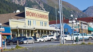 A building with a sign reading "BROWN & HAWKINS" in front of a mountainous backdrop. - Historic Apartment in Downtown Seward (Seward)