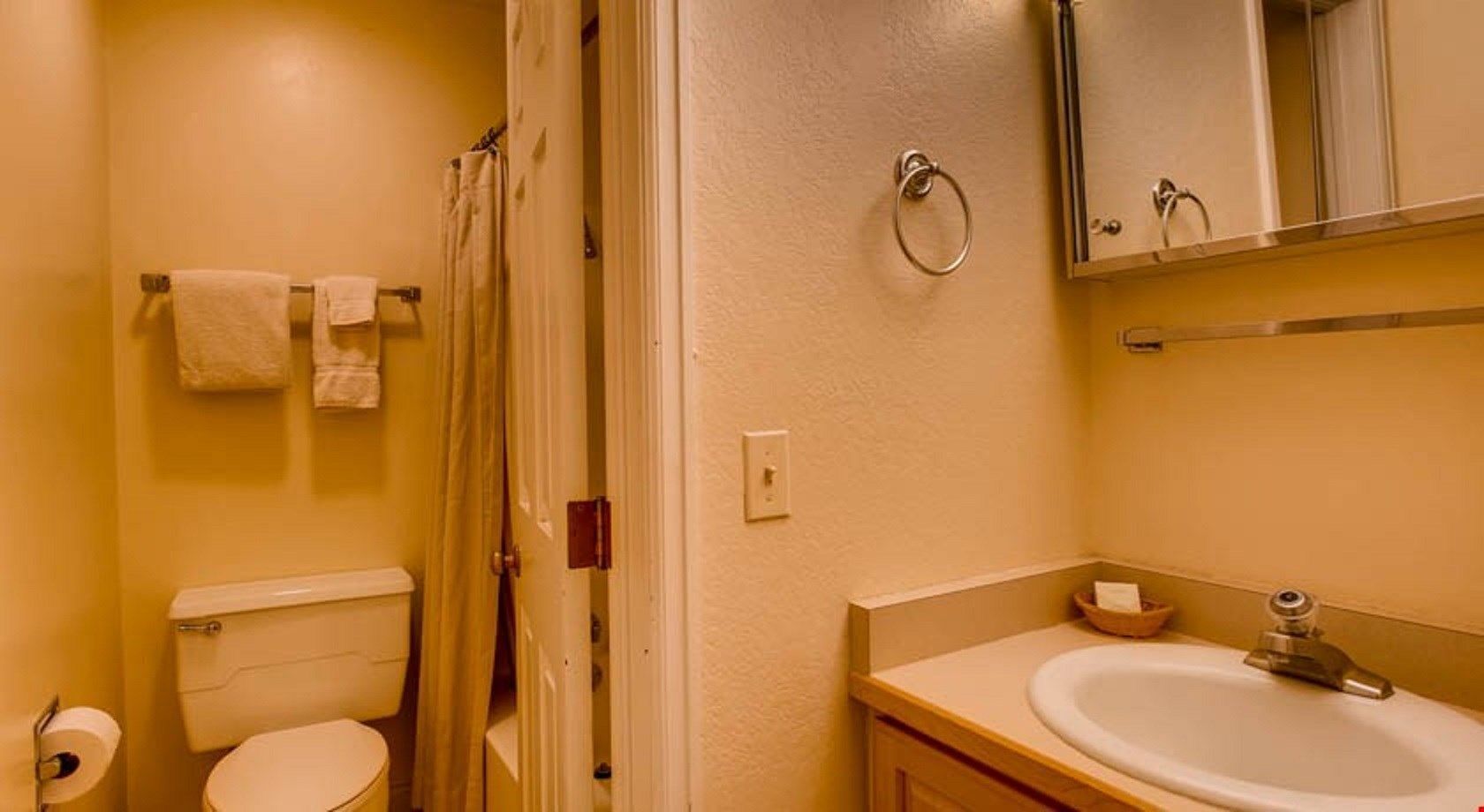 A bathroom with a toilet, sink, and mirror.