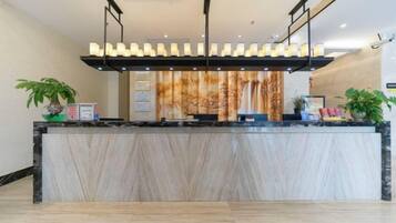 Un comptoir d’accueil avec un revêtement en marbre, un luminaire suspendu et un mur orné d’un tableau vertical.