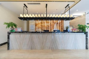 Un comptoir d’accueil avec un revêtement en marbre, un luminaire suspendu et un mur orné d’un tableau vertical.