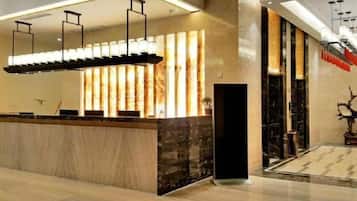 A reception area with a marble counter, modern pendant lighting, and a large vertical light display.