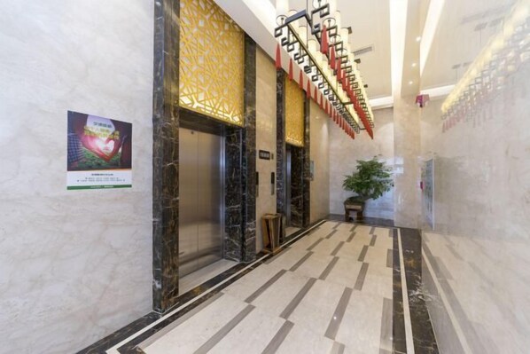 A hallway with marble flooring, a staircase with red and white accents, and a potted plant. - Weiyina Hotel (Renhua)