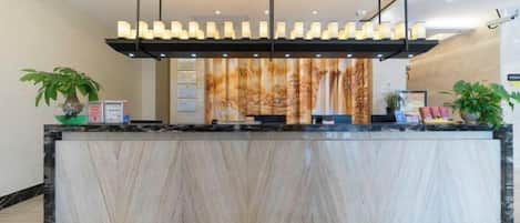 A reception area with a marble counter, a plant, and a decorative light fixture.