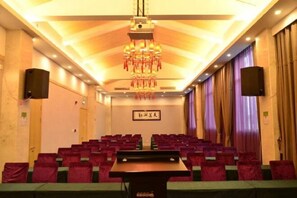 A conference room with rows of chairs, a podium, and a chandelier.