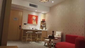 Une chambre d’hôtel avec un coin repas, un fauteuil rouge, une petite table et un tableau au mur.