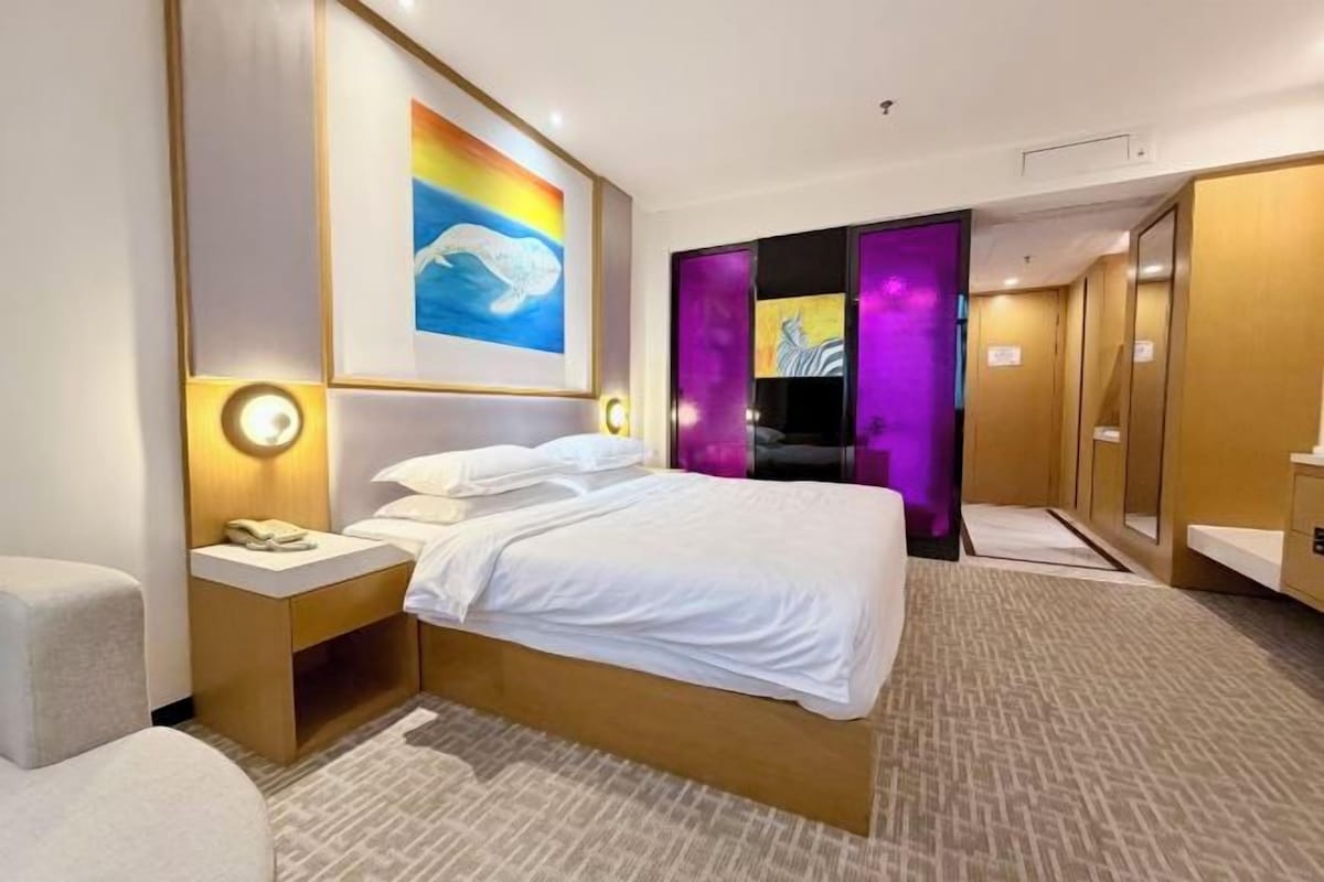 A hotel room with a bed, bedside tables, a TV, and a bathroom with a mirror and sink.