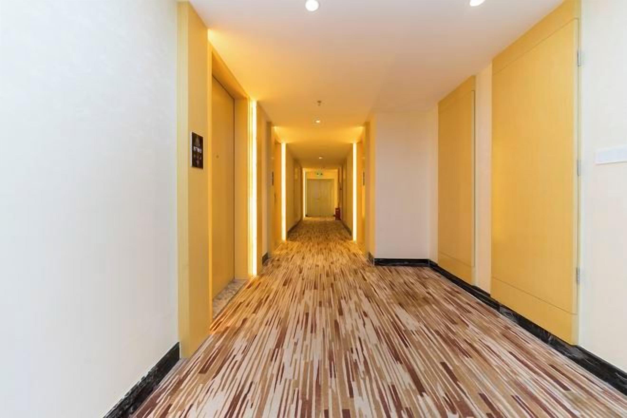 A hotel corridor with a carpeted floor and doors on both sides.