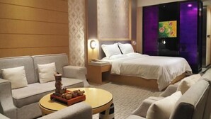 Una habitación de hotel con una cama, un sofá, una mesa de centro y una mesita de noche.