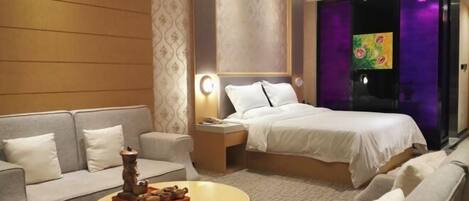A hotel room with a bed, a sofa, a coffee table, and a nightstand.