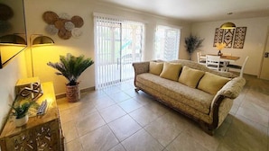 Sala de estar com sofá, luminária, planta e um objeto decorativo na parede.