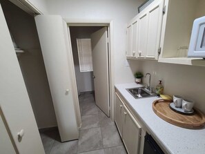 A compact kitchen with a sink, countertop, and cabinets.