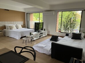 A modern hotel room with two beds, a TV, a small table, and a chair. - Apartment at Poblado Park Studio Apartment  (Medellín)