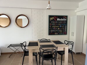 A dining area with a wooden table and black chairs, a white brick wall, and two round mirrors. - Apartment at Poblado Park Studio Apartment  (Medellín)