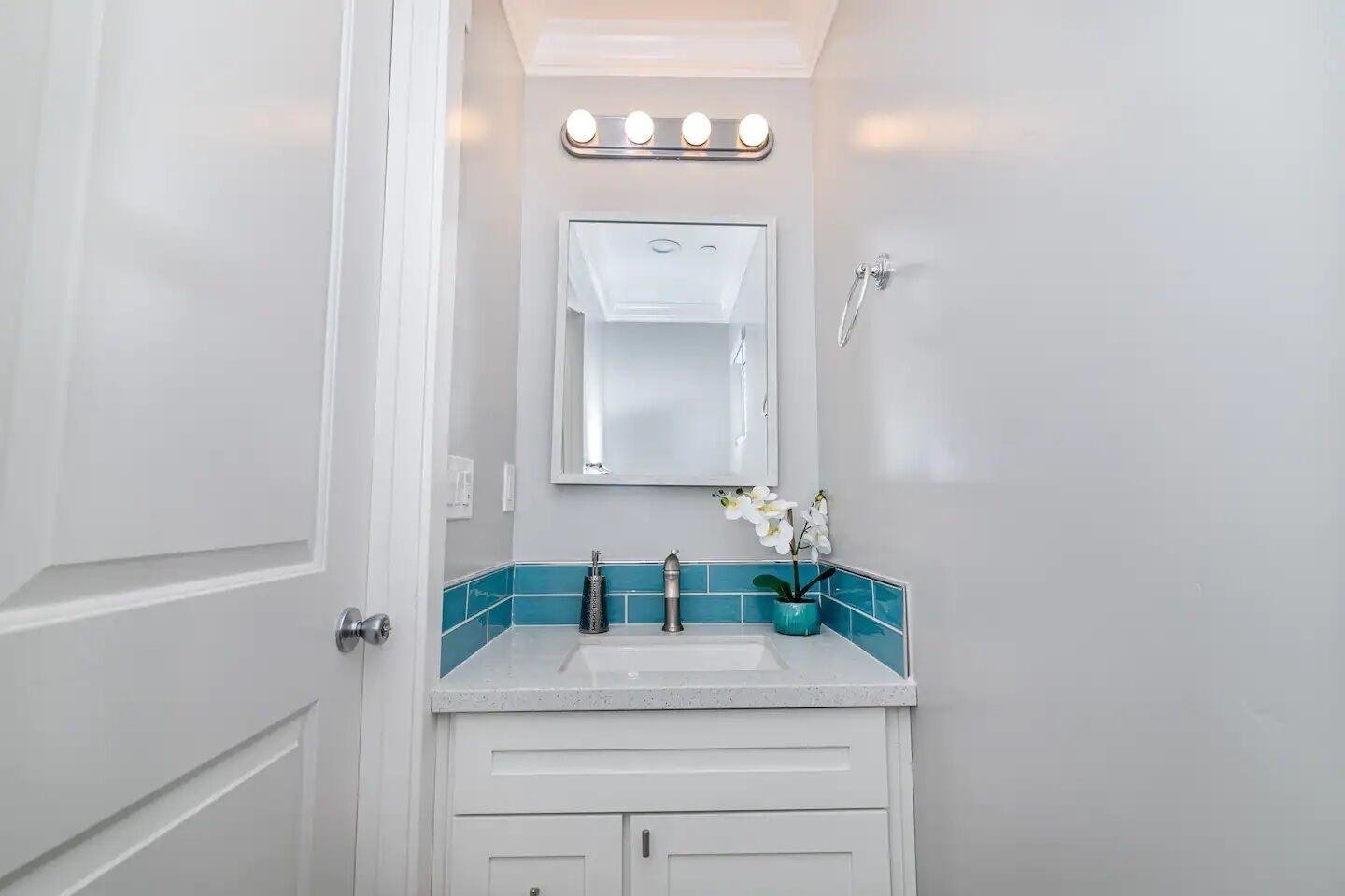 Un baño con tocador blanco, espejo, lavamanos y ducha.