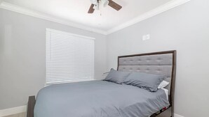 A bedroom with a bed, white walls, a ceiling fan, and a window with blinds. - Close to Sac DT🏨 Charming&Cute 🛌Brand New House😊 (Sacramento)