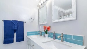 A bathroom with two sinks, a large mirror, and blue towels on the wall. - Close to Sac DT🏨 Charming&Cute 🛌Brand New House😊 (Sacramento)