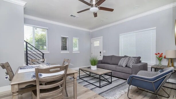 A spacious living room with a gray sofa, a coffee table, and a blue chair. There is a dining area with a wooden table and chairs. - Close to Sac DT🏨 Charming&Cute 🛌Brand New House😊 (Sacramento)