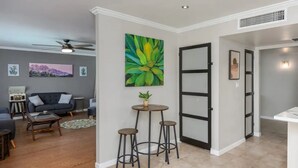 Un salón moderno con un sofá oscuro, una mesa de centro y un cuadro de un cactus.