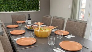A dining table set with plates, glasses, and a bowl of salad. - Heated Pool/Hot tub in heart of Tempe/ASU/Scottsdale (Tempe)