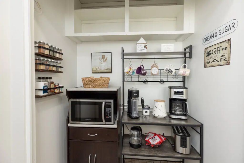 A compact kitchen with a microwave, coffee maker, and storage shelves.