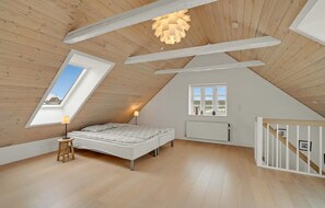 A bedroom with a sloped ceiling, a skylight, a bed, a radiator, and a window with a view. - Awesome home in Thisted with kitchen (Thisted)