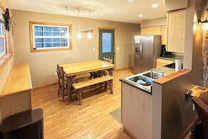 Une cuisine dotée de plans de travail en bois, d’un îlot central intégré, d’un réfrigérateur et d’un coin repas avec une banquette.