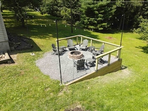 Un espace extérieur aménagé, abrité et doté de chaises Adirondack, d’un foyer et d’une terrasse en bois.