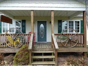 A house with a porch, a front door, and two large wooden wheels.