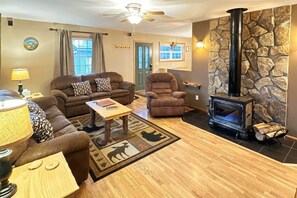 Un salon chaleureux avec une cheminée, un canapé, un fauteuil, une table basse et un tapis à motifs animaliers.