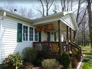 A white building with a porch, a sign reading 'Spring View Lodge,' and a wooden staircase leading up to the porch.