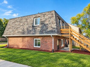 A two-story house with a brick facade and a wooden staircase leading to the second floor. - Remodeled apartment in central location (Council Bluffs)
