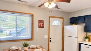 A kitchen with a dining table set for four, a white refrigerator, and a ceiling fan. - Remodeled apartment in central location (Council Bluffs)