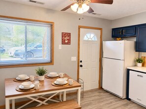 A kitchen with a dining table set for four, a white refrigerator, and a ceiling fan. - Remodeled apartment in central location (Council Bluffs)