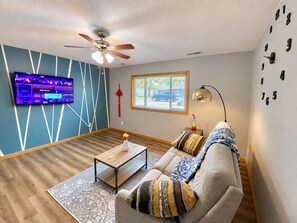 A living room with a sofa, coffee table, TV, and a ceiling fan.