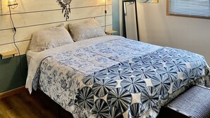 A bedroom with a bed, a ceiling fan, a wall-mounted light, a poster, and a window with blinds. - Remodeled apartment in central location (Council Bluffs)
