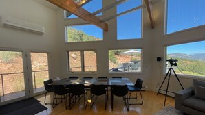 Una habitación amplia con una gran mesa y sillas, ventanas grandes con vistas al exterior y un telescopio sobre un trípode.