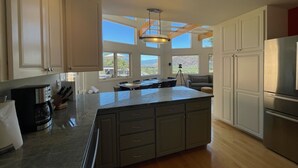 Una cocina moderna con una isla grande, vigas de madera y ventanas amplias que ofrecen vistas del exterior.