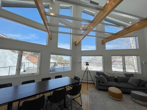 A spacious room with large windows, a dining table, and a sofa. - Epic Mountain Chalet – Jaw-Dropping 180° Views! (Durango)