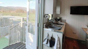 A modern kitchen with a large window, a built-in oven, and a sink. - Erw Glas Glamping and Camping (Llanrwst)