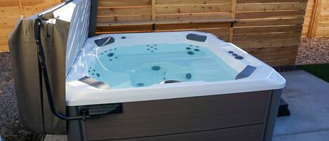 A hot tub with a wooden deck and a wooden fence in the background.