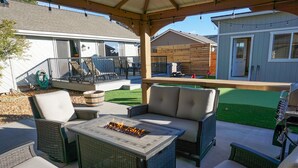 Une terrasse extérieure aménagée avec des meubles en osier, un foyer et une vue sur le jardin.