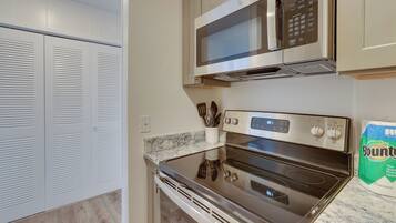 A kitchen with a stainless steel microwave, oven, and a set of knives in a holder.